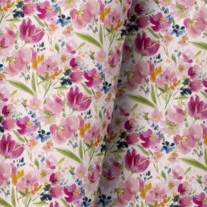 以下が含まれることがあります： 水彩画のフローラルパターンが施された生地のクローズアップ。デザインは、白の背景にピンク、フクシア、黄色、青の花と緑の葉が特徴です。生地は折りたたまれており、素材の質感と深さを示しています。