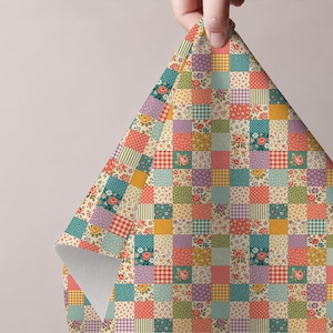 Puede incluir: Una hoja de papel de regalo con un patrón de cuadrícula de patchwork repetitivo. El diseño consta de cuadrados alternos en varios colores, incluyendo verde azulado, amarillo, rojo y morado, decorados con estampados florales, cuadros vichy y rayas.