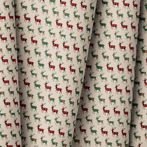 May include: A fabric with a repeating pattern of red and green reindeer on a cream background. The reindeer are stylized with antlers and are evenly spaced across the fabric. The fabric is folded, showing the pattern's continuity.