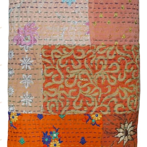 May include: A patchwork quilt with a variety of colors and patterns. The quilt features embroidered floral designs in blue, pink, and white, along with orange and peach-colored sections. The quilt is rectangular and appears to be made of fabric.