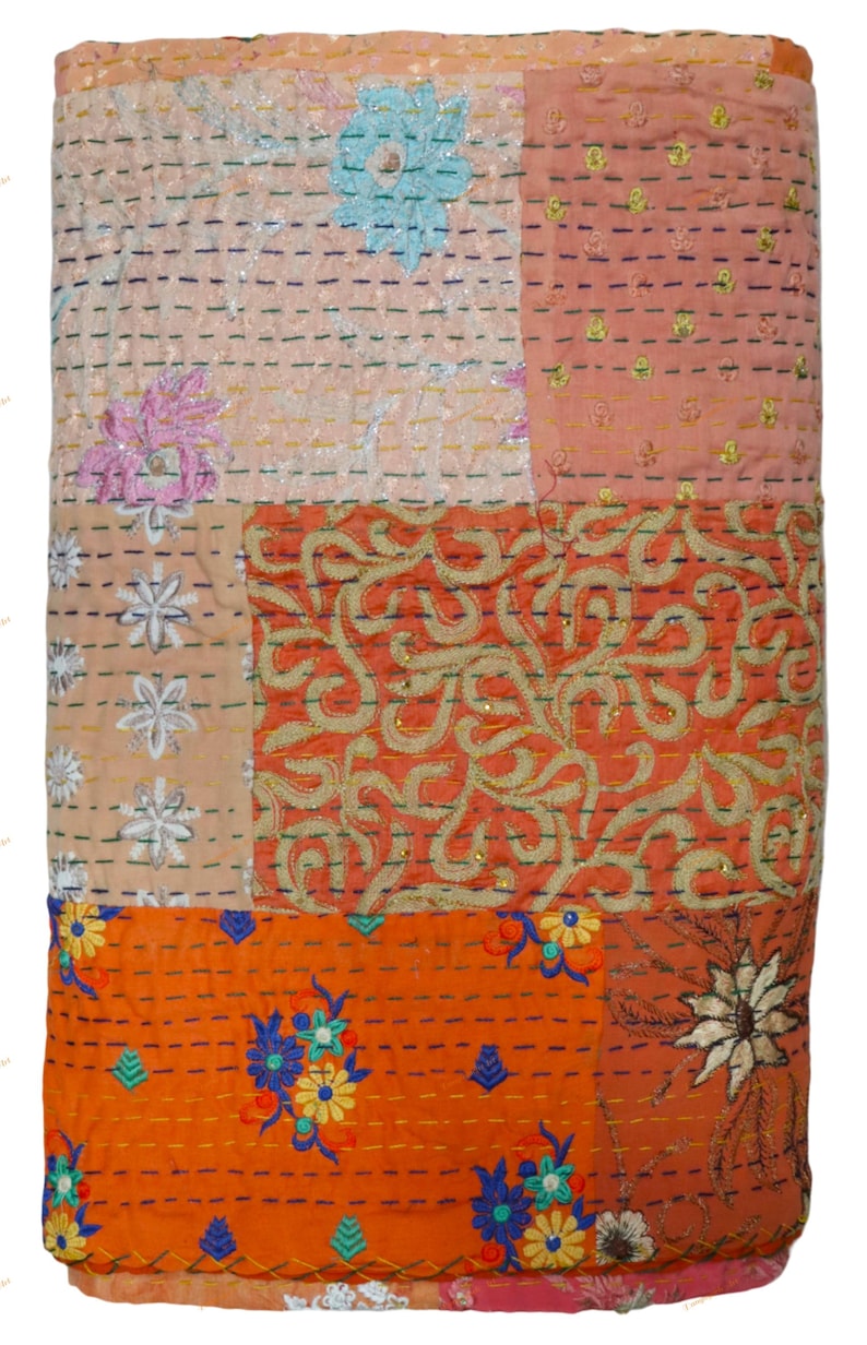 May include: A patchwork quilt with a variety of colors and patterns. The quilt features embroidered floral designs in blue, pink, and white, along with orange and peach-colored sections. The quilt is rectangular and appears to be made of fabric.