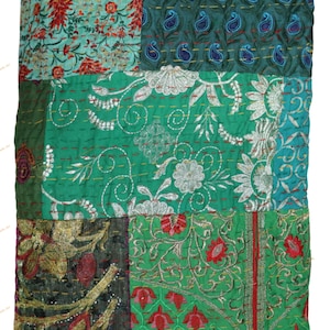 May include: A patchwork quilt with a variety of embroidered patterns. The quilt features squares of teal, green, and dark green fabric. Some squares have floral designs, while others have paisley or embroidered details. The quilt is a mix of textures and colors.