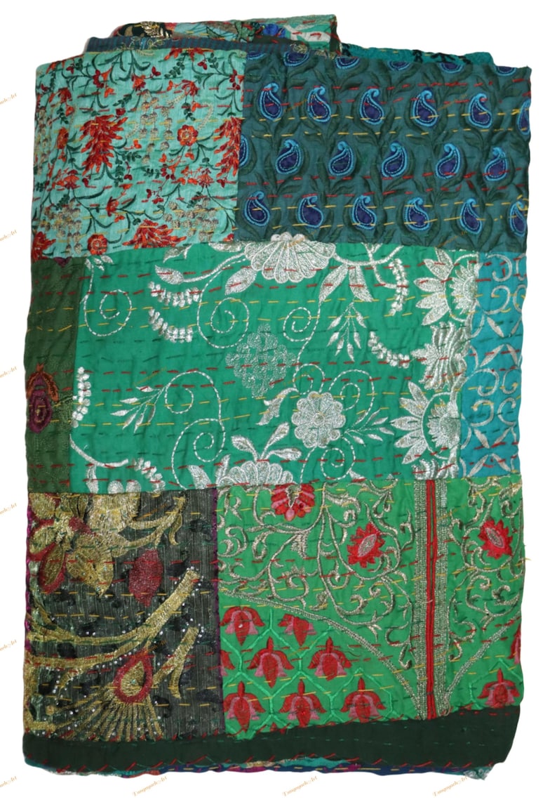 May include: A patchwork quilt with a variety of embroidered patterns. The quilt features squares of teal, green, and dark green fabric. Some squares have floral designs, while others have paisley or embroidered details. The quilt is a mix of textures and colors.