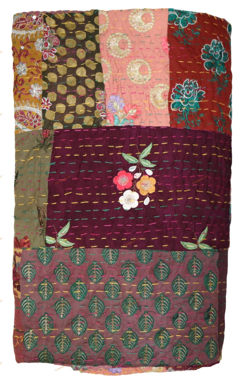 May include: A patchwork quilt with a variety of patterned fabrics in shades of brown, pink, and burgundy. The quilt features floral and leaf motifs, with embroidered details and colorful stitching. The overall design is a mix of textures and patterns.