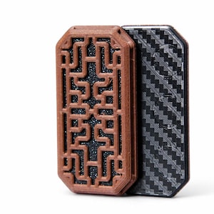 May include: Two rectangular decorative objects. One is brown with a geometric openwork design, revealing a dark, speckled interior. The other is black with a textured, checkered pattern. Both have rounded corners and a layered appearance.