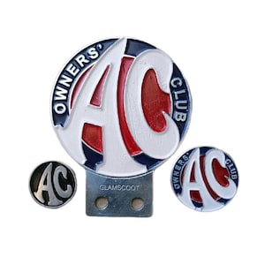 May include: A set of three AC Owners Club badges. The largest badge is round with a white "AC" design on a red background, surrounded by a blue border and the words "OWNERS CLUB". A smaller badge and a pin are also included.