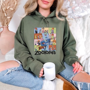 Pu&ograve; includere: Felpa con cappuccio verde oliva con una grafica colorata dei personaggi del film d'animazione "Zootropolis". La grafica &egrave; una griglia di immagini con il titolo del film in nero. La felpa ha un cappuccio con coulisse e una tasca a marsupio.