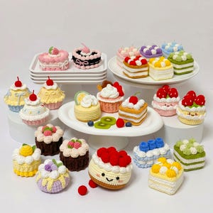 Puede incluir: Una colección de varios pasteles y dulces en miniatura tejidos a ganchillo en diversos colores, incluyendo rosa, amarillo, marrón, verde y azul. Estos artículos hechos a mano presentan detalles decorativos como cerezas, bayas y copetes de crema.