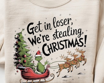 May include: Cream-colored sweatshirt featuring a graphic of the Grinch in a sleigh with reindeer, a Christmas tree, and the text "Get in loser, We're stealing CHRISTMAS!". The design is in red, green, and black.