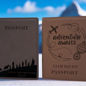 May include: Two passport holders, one gray and one tan, are displayed. The gray passport holder has the word "PASSPORT" and a black silhouette of figures. The tan passport holder has the words "adventure awaits" and a globe design.