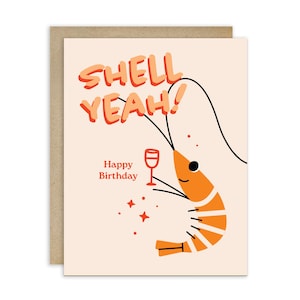 May include: A greeting card with a cartoon shrimp holding a wine glass. The card has the words "SHELL YEAH!" in orange and "Happy Birthday" in brown. The shrimp is orange with white stripes.