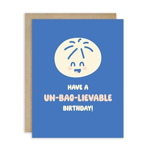May include: A greeting card with a blue background and a cartoon dumpling illustration. The text "Have a Un-Bao-Lievable Birthday!" is written in pink. The card is on a brown background.