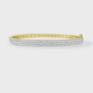 Op de afbeelding: Een gouden armband met drie rijen kleine, sprankelende witte edelstenen. De armband heeft een scharnierende sluiting en een gladde, gepolijste afwerking. De edelstenen zijn dicht op elkaar gezet, waardoor een doorlopende band van glans ontstaat.