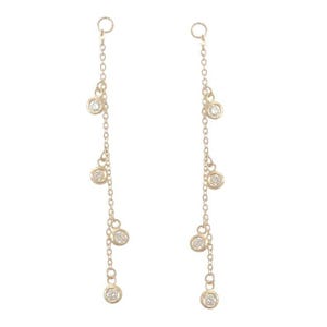May include: A pair of gold drop earrings featuring delicate chains. Each earring is suspended from a small circular hoop and adorned with four evenly spaced, bezel-set round clear stones that dangle vertically along the fine gold chain.