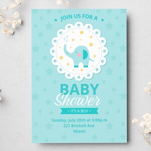 Puede incluir: Invitación a un baby shower con fondo azul claro y detalles florales blancos. La invitación presenta una ilustración de un elefante azul con un chorro de agua, rodeado de estrellas. El texto incluye "Baby Shower" y "It's a Boy."