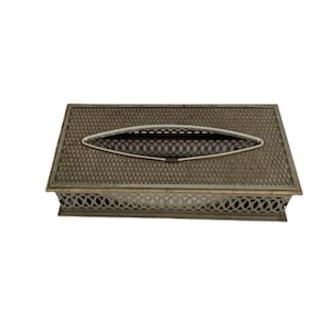 May include: A rectangular tissue box with a textured, bronze-colored lid and a decorative, openwork design around the sides. The lid features a silver-toned, oval opening for tissue dispensing.