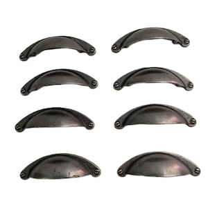 May include: A set of eight dark gray metal cup drawer pulls arranged in two vertical columns. Each handle features a curved, semi-circular design with a smooth finish and two small screw holes on the ends for mounting to furniture or cabinetry.