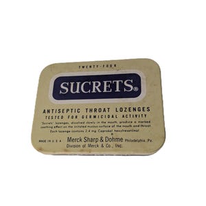 May include: Vintage Sucrets antiseptic throat lozenges tin. The rectangular tin has rounded corners and a cream-colored background. The text "SUCRETS" is in a navy blue rectangle. The tin reads "ANTISEPTIC THROAT LOZENGES" and "MADE IN USA".