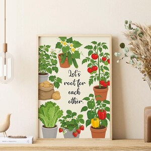 May include: A rectangular wall art print featuring a cream background with illustrations of potted vegetables and fruits, including tomatoes, peppers, cucumbers, lettuce, strawberries, and potatoes. The text Let's root for each other is centred.
