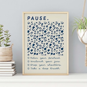 May include: A framed wall art print on a light cream background featuring the word PAUSE in dark blue at the top. Below is a repeating pattern of dark blue stylized flowers. Four lines of text follow, each preceded by a flower icon: Relax your forehead, Unclench your jaw, Drop your shoulders, and Take a deep breath.