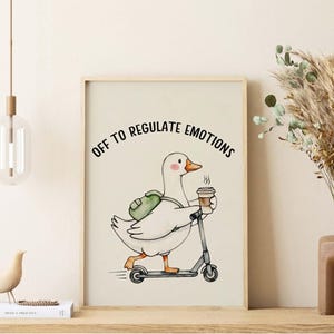 May include: A framed wall art print featuring a white goose with a green backpack riding a grey scooter while holding a steaming coffee cup. The text above the goose reads OFF TO REGULATE EMOTIONS in black capital letters against a cream background.