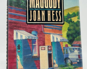Mischief In Maggody, firmado por Joan Hess, es un libro de misterio clásico de tapa dura.