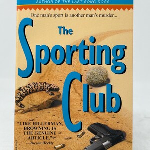 May include: Book cover for "The Sporting Club" by Sinclair Browning. The cover features a desert scene with a lizard, tumbleweed, and a handgun. The title is in large blue letters, with the author's name at the top.