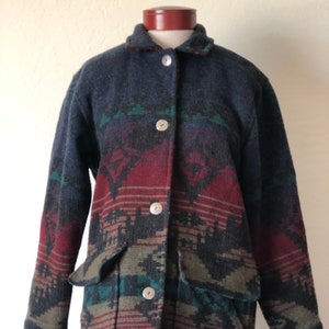 May include: A dark blue, red, green, and brown patterned jacket with a button-up front and two pockets.