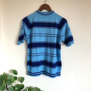 May include: A blue and navy striped short-sleeved sweater with a mock neck.