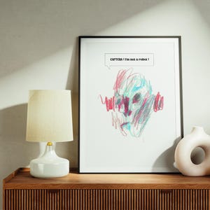 Peut inclure: Une œuvre d'art encadrée avec un dessin de visage abstrait coloré. Le texte "CAPTCHA! I'm not a robot!" est dans une bulle. Une lampe blanche, un vase blanc en forme de donut et un petit vase marron sont sur une surface en bois.