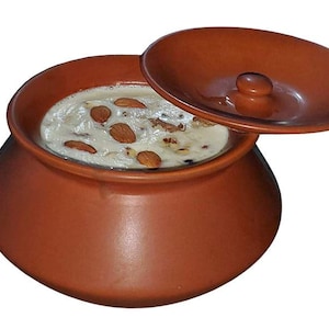 May include: A terracotta-coloured earthenware pot filled with a creamy dessert, garnished with almonds. The lid is partially open, revealing the contents. The pot has a rounded shape and a small handle on the lid.