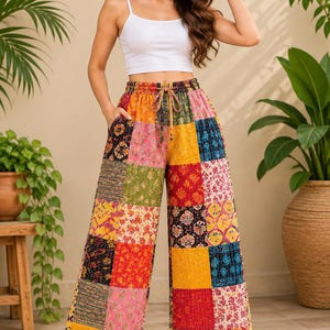 May include: Wide-leg pants featuring a colorful patchwork design with various floral and geometric patterns in shades of yellow, red, pink, green, and blue. The pants have an elasticized waistband with a drawstring tie and side pockets.