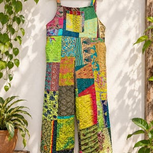 May include: A sleeveless jumpsuit featuring a patchwork design made from various colorful fabrics with intricate patterns, including floral, geometric, and animal motifs. The garment has wide legs and is constructed with visible stitching.