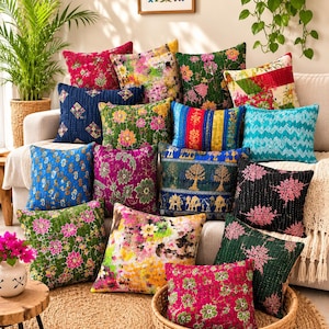 Könnte beinhalten: Eine Sammlung quadratischer Dekokissen mit verschiedenen bunten Mustern, darunter Blumenprints, geometrische Formen und Tiermotive. Die Kissen bestehen aus gestepptem Stoff mit sichtbaren Nähten und sind auf einem Sofa sowie in einem Korb angeordnet.