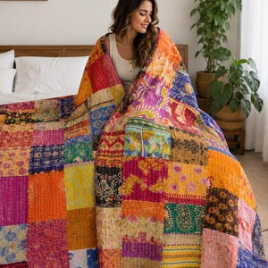 Könnte beinhalten: Eine große, rechteckige Patchwork-Decke mit einer Vielzahl von bunten Stoffquadraten. Die Decke zeigt verschiedene komplizierte Muster, florale Motive und geometrische Designs in den Farben Orange, Pink, Violett, Blau und Gelb.