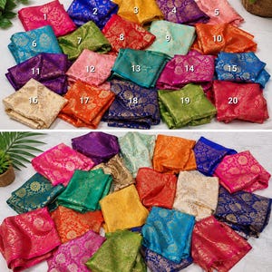 May include: A collection of twenty folded fabric squares featuring intricate gold floral brocade patterns in various colors including pink, blue, yellow, purple, orange, green, and cream. Each square is numbered from one to twenty for identification.