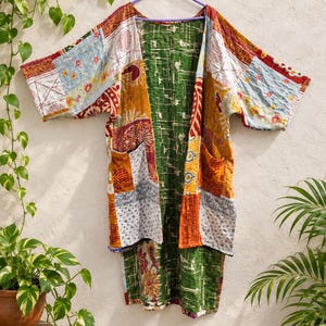 May include: A long-sleeved open-front jacket featuring a patchwork design with various floral and geometric patterns in shades of orange, green, blue, and white. The garment has two front pockets and visible stitching throughout the fabric.