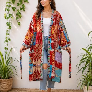 May include: A long-sleeved, open-front kimono jacket featuring a vibrant patchwork design with various red, blue, and yellow patterned fabric panels. The garment includes a matching tie belt, two front pockets, and visible kantha-style stitching.