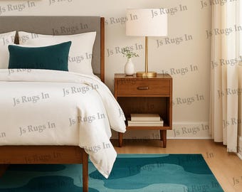 May include: A teal and light blue patterned area rug in a bedroom setting. The rug is rectangular with an abstract design. The bedroom features a bed with white bedding, a wooden nightstand, and a framed artwork.