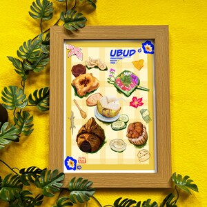 May include: A framed print showcasing a vibrant illustration of diverse vegan dishes. The print displays the word "Ubud" alongside "Vegan Food" and "Beauty Vibes". The artwork is set against a yellow checkered backdrop and enclosed in a light brown wooden frame.