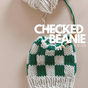 May include: A handmade green and white checkered beanie with matching yarn. The text "CHECKED BEANIE" is displayed on the image. The beanie is in the process of being knitted with wooden needles.