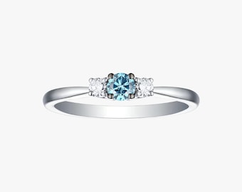 May include: A silver ring with a central light blue gemstone flanked by two smaller white gemstones. The ring has a simple, elegant design, perfect for everyday wear or special occasions.