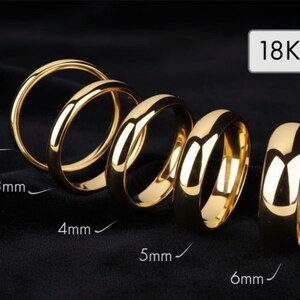 May include: A selection of gold rings, ranging from 2mm to 6mm in width, presented against a dark backdrop. The rings have a polished finish, reflecting light. The text "18K" is displayed, signifying the gold's purity.