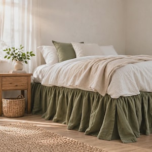 Può includere: Un letto con una balza a volant in tinta unita verde oliva, un copripiumino bianco e una coperta beige. Il letto è completato da due cuscini bianchi e un cuscino quadrato verde oliva, creando un look a strati con biancheria da letto neutra.