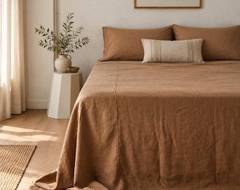 May include: A solid brown bed sheet set featuring two matching pillowcases and a rectangular accent pillow with vertical cream-colored stripes. The bedding is draped over a bed frame, showcasing a textured fabric finish across the surface.