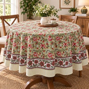 Puede incluir: Un mantel redondo con fondo verde salvia y un patrón floral repetitivo en tonos rojo, blanco y verde oscuro. La tela tiene un borde ancho con un estampado floral más pequeño y un borde fino a rayas en color verde claro y blanco.