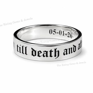 May include: A polished silver-toned band ring featuring black engraved text on the exterior that reads till death and after. The interior of the ring is engraved with the date 05-01-26. The metal surface is reflective and smooth throughout.