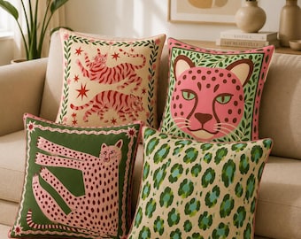 Peut inclure: Quatre coussins carrés décoratifs aux motifs animaliers. Un coussin présente deux tigres rouges sur fond crème, un autre un visage de léopard rose, un troisième un léopard rose sur fond vert, et le quatrième arbore un imprimé léopard.