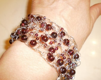 Gennaio è per i granati. Bracciale in filo all'uncinetto con perline di granato rosso intenso.