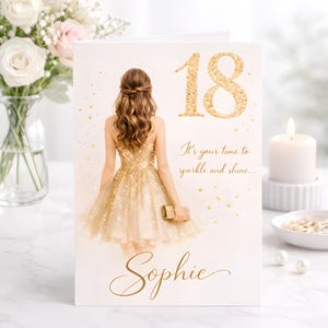 Puede incluir: Tarjeta de felicitación de cumpleaños con un "18" dorado con purpurina y el nombre "Sophie" en escritura elegante. La tarjeta presenta una ilustración de una mujer con un vestido dorado. El texto dice "It's your time to sparkle and shine..."
